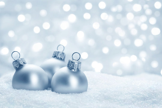 three grey christmas balls on snow 