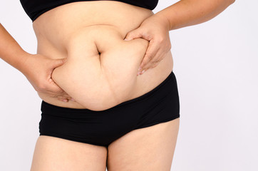 Woman's fingers measuring her belly fat