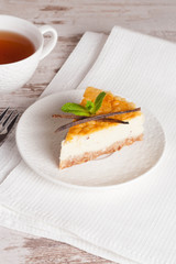 Vanilla cheesecake on a white plate and cup of tea, vertical