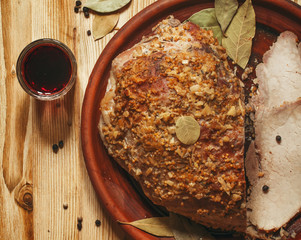 Baked ham with spices on a clay plate on a wooden table, top vie