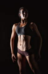 fitness woman in sport style standing against black background