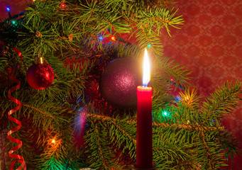 Red candle on a background of Christmas tree