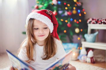Beautiful girl, reading a book in front of the Christmas tree