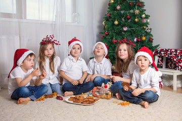 Six adorable children, having fun in front of the Christmas tree