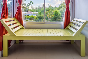 Modern green wooden bench nearby window. It is furniture for interior decoration.