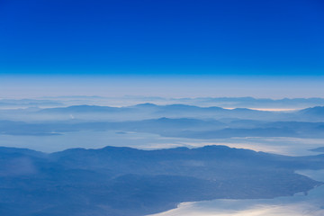Fototapeta na wymiar Deep blue sky above landscape with mountains and sea,atmospheric aerial photography