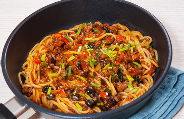 spaghetti with vegetables and minced meat in a frying pan