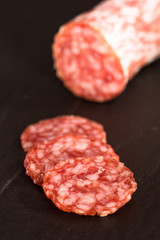Salamischeiben mit einer Salami im Hintergrund