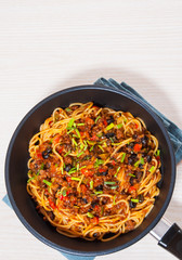 spaghetti with vegetables and minced meat in a frying pan