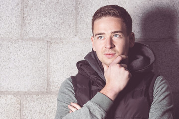 Obraz premium Nachdenklicher junger Mann vor Betonsteinmauer