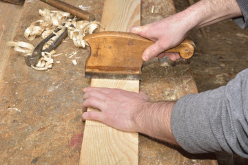 carpenter working with plane on wooden