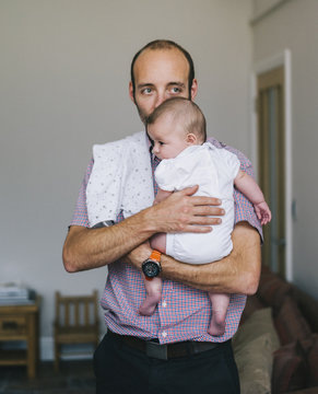 A man holding a young baby close to his chest. 