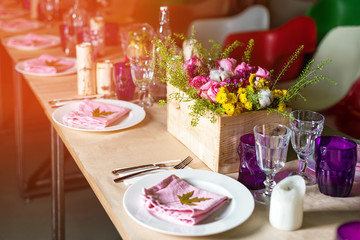 Decorated table ready for dinner. Beautifully decorated table set with flowers, candles, plates and serviettes for wedding or another event in the restaurant.