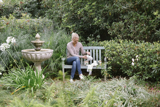 Woman sitting on a wooden bench in a garden, taking a break.