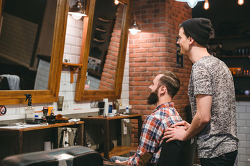 Smiling hairstylist and plesed man client looking in mirror