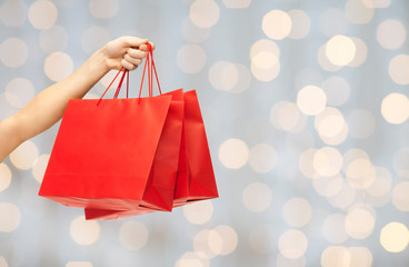 close up of hand holding red shopping bags