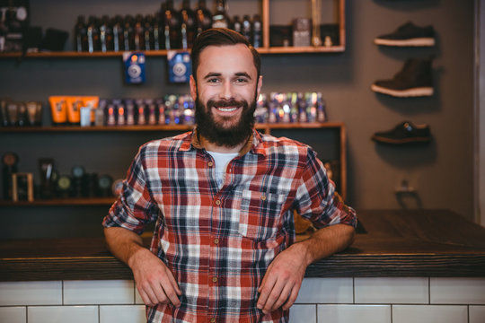 Happy cheerful man with beard in barbershop after visiting barber