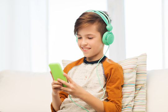 happy boy with smartphone and headphones at home