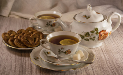 teapot and cups of tea with lemon and pretzels