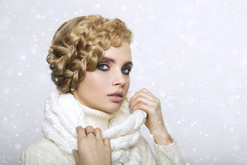 portrait of a beautiful young blonde woman on a light background. hair tied in a braid. girl wearing a warm sweater and scarf. copy space..