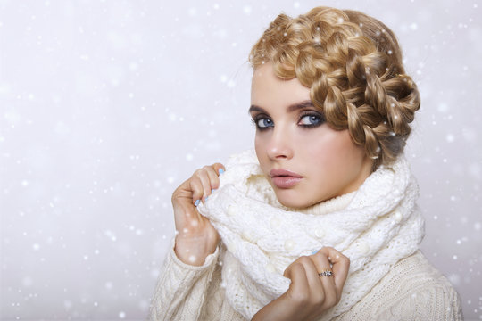 portrait of a beautiful young blonde woman on a light background. hair tied in a braid. girl wearing a warm sweater and scarf. copy space..