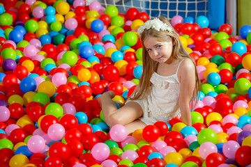 A girl in the playing room with many little colored balls