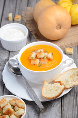 Pumpkin soup with pumpkin seeds and croutons on the rustic wooden table