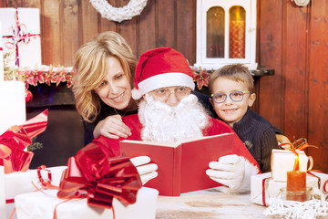 Obraz na płótnie Canvas mother and son look at wish list with santa claus