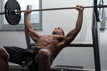 Fototapeta na wymiar Muscular Man Doing Bench Press Exercise For Chest