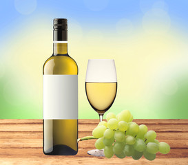 bottle of white wine, glass and green grape on wooden table over