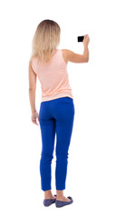 back view of standing young beautiful  woman  and using a mobile