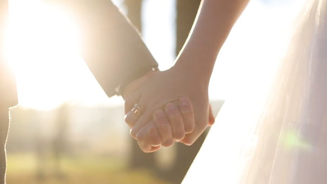   Close up of wedding couple holding hands at sunset 