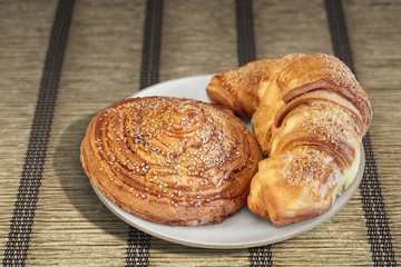 Croissant Puff Pastry Snail Rolls Sprinkled with Sesame Seeds on Parchment Plated Place Mat.