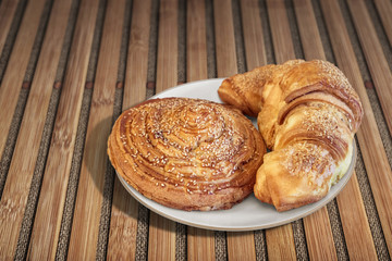 Croissant Puff Pastry Snail Rolls Sprinkled with Sesame Seeds on Bamboo Place Mat.