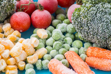 frozen vegetables: broccoli, cherry tomatoes, corn, pea, carrot on blue plate