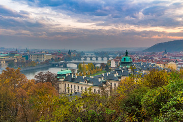 Naklejka premium General view of bridges in Prague in autumn. Yellow trees flavor the cityscape. Fog over the city.
