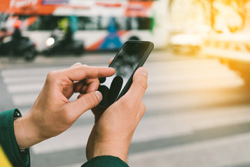 Closeup of hands using smartphone in the street with flare effects