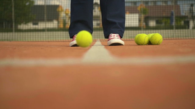 Player feet throwing tennis balls on the court – slow motion