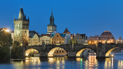 Fototapeta na wymiar Evening view of the Charles Bridge in Prague, Czech Republic, with Old Town Bridge Tower, Old Town Water Tower and dome of the National Theatre