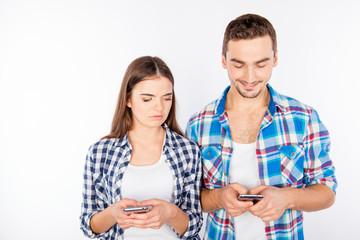 Cheerful man typing message ignoring his girlfriend