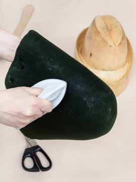 hatter gluing a felt hood for shaping on dummy