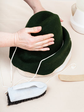 hatter fixes a felt hood on dummy for shaping