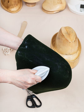 hatter gluing a felt hood for shaping on hat-block