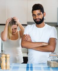 interracial family couple with serious faces quarrelling in kitc