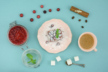 Coffee and chocolate cake with cranberry jam and cinnamon on wooden board, over turquoise background. Top view.