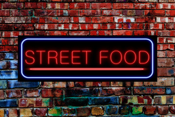 Street Food Neon sign on a Graffiti. Bricks wall