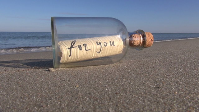 Message in a bottle with words “for you” on the ocean  beach