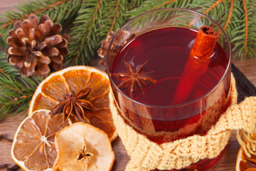 Glass of mulled wine wrapped scarf, spices and spruce branches
