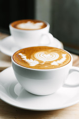 Selective focus cup of hot latte art coffee on wooden table,focus at white foam