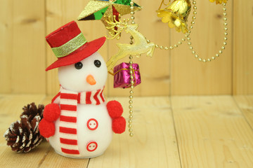 Toy snowman  is standing beside Christmas decoration
